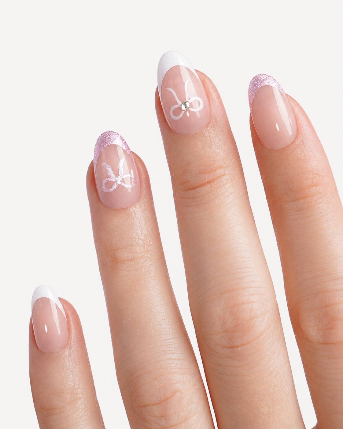 Close-up of Lover's Note almond press-on nails featuring elegant French tips, pink glitter edges, and delicate bow nail art for a romantic manicure look