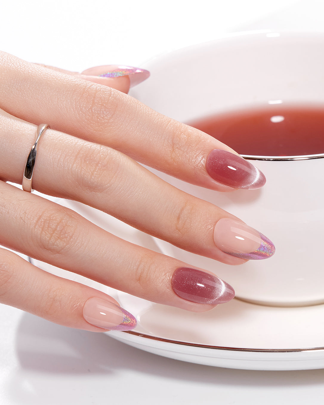 Potion berry red and nude pink press-on nails styled on hands with glossy gel finish and holographic glitter French tips for an elegant everyday manicure look