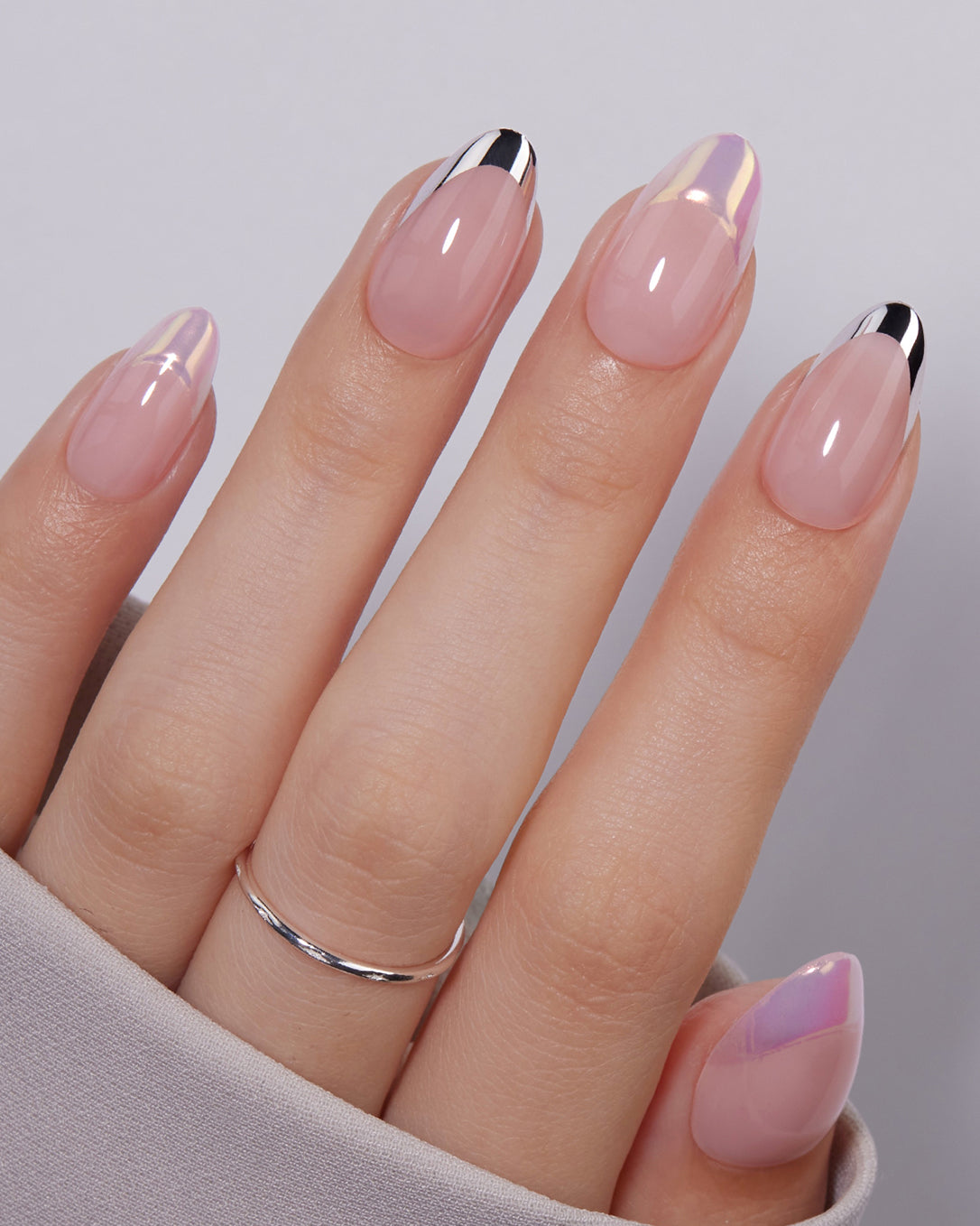 Discours nude metallic French tip press-on nails styled on hands creating a sophisticated minimalist manicure look for elegant occasions