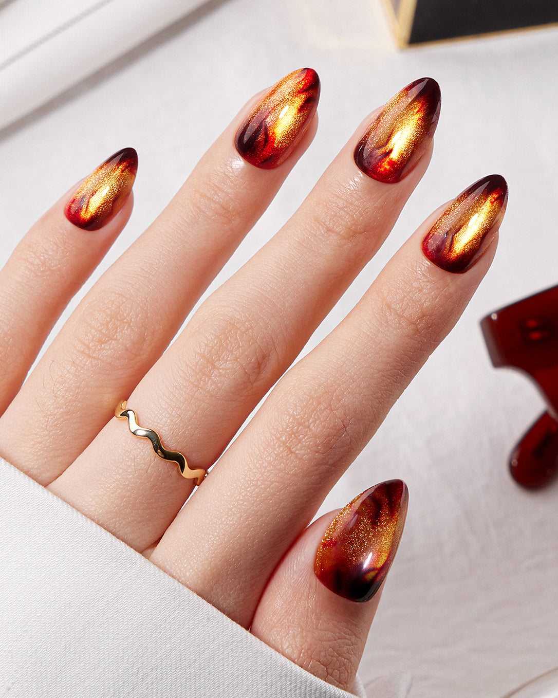 Model wearing VSALON Amber Whisper press-on nails featuring a luxurious golden brown cat-eye manicure with a fiery molten effect.