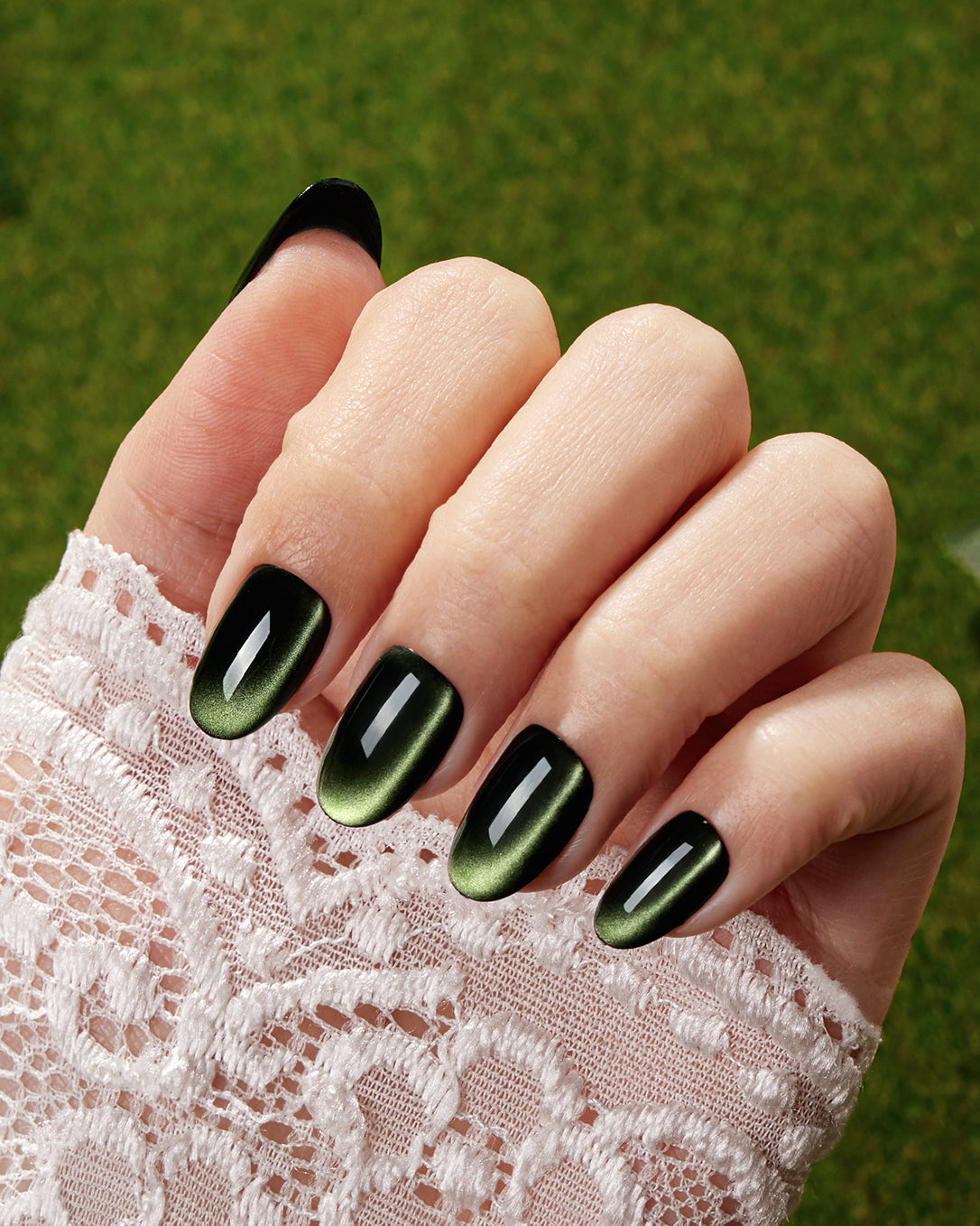 Model wearing VSALON Velvet Moss press-on nails featuring an elegant emerald green cat-eye manicure with a jewel-inspired shimmer.