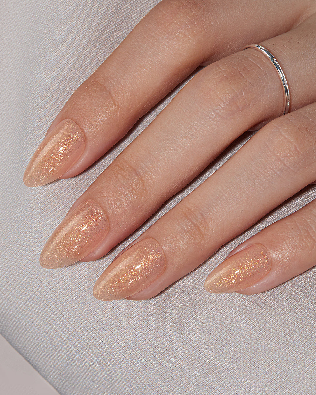 Dancing Firefly gold shimmer almond press-on nails creating an elegant neutral everyday manicure look