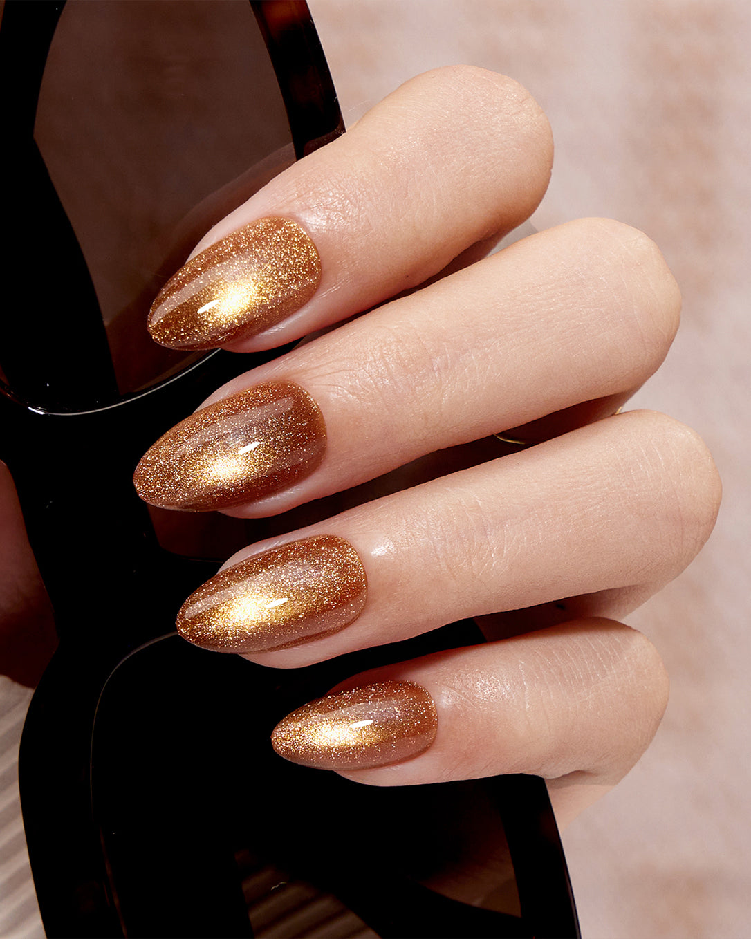 Model wearing VSALON Truffle Halo press-on nails featuring a luxurious golden cat-eye manicure with a cozy winter-inspired style.