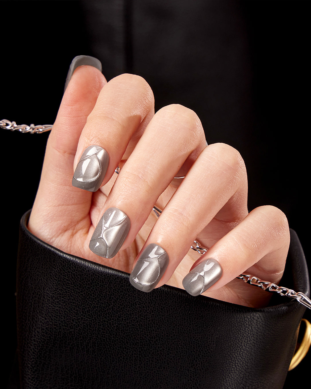 Model wearing VSALON Metropolis Beam press-on nails featuring a minimalist grey-silver cat eye manicure with a modern metallic glow.