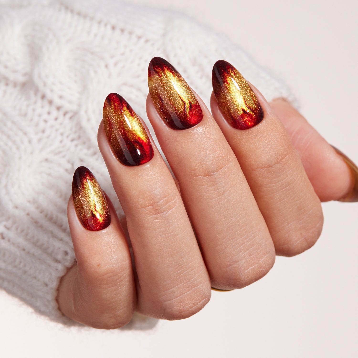 VSALON Nourishment Amber Whisper Golden Brown Cat Eye Flame Medium Almond Press On Nails - Close-up of model's hand bending fingers to hold VSALON press on nails – highlighting nail design and color details